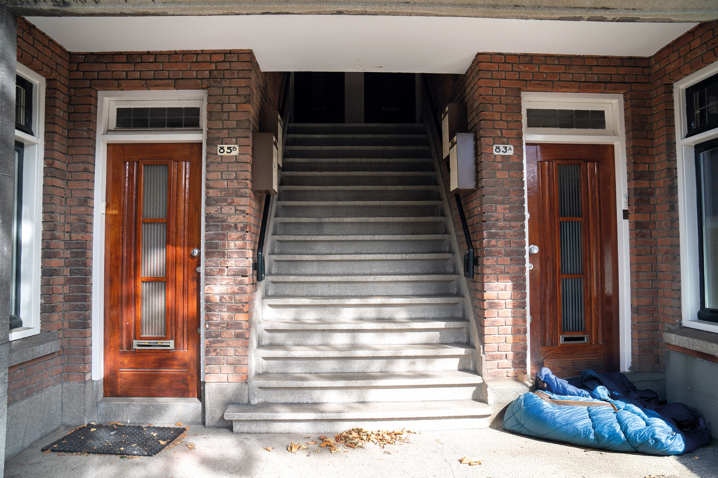 Foto van een portiekwoning met een dakloze in een slaapzak
